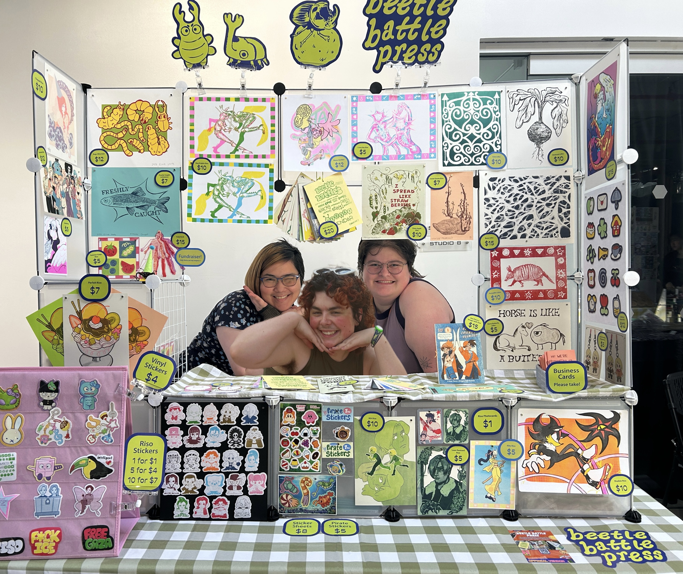 Beetle Battle Press posing at their art vending table at MoshiMoshi Market in May 2026